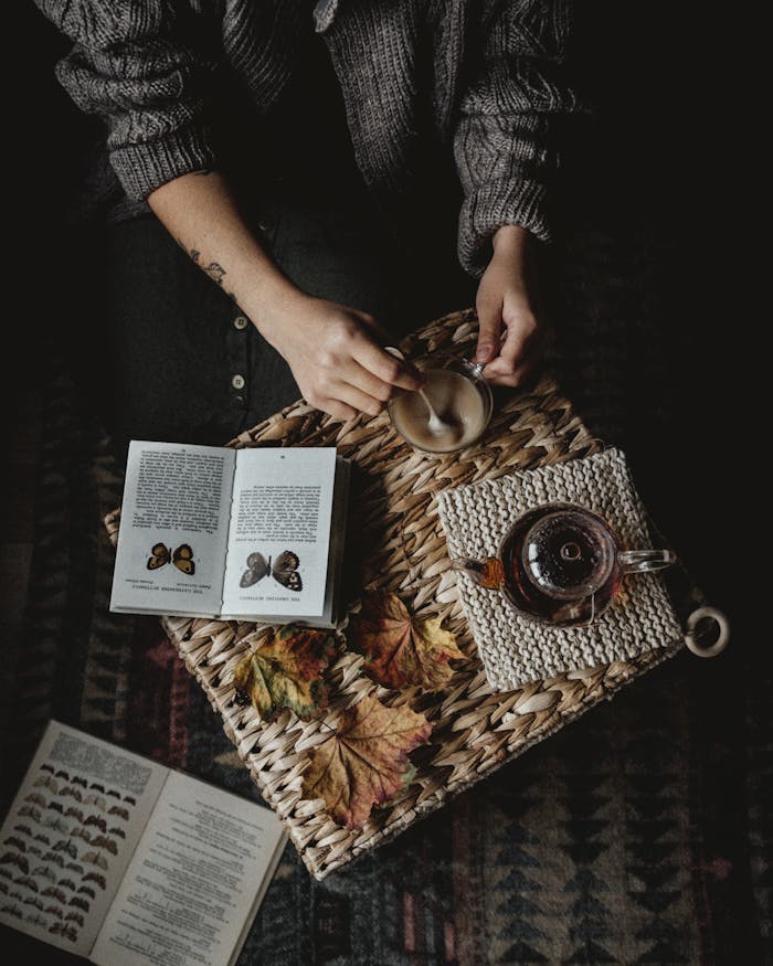who-we-are From above of crop faceless person holding cup of fresh coffee while sitting at table and reading book about butterflies